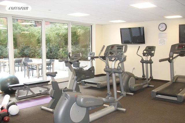 exercise room with visible vents, a wall of windows, and baseboards