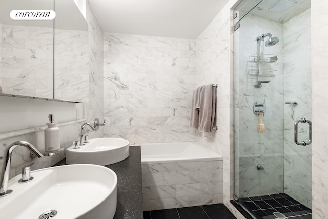 full bathroom featuring tiled tub, tile walls, a stall shower, and dual sinks