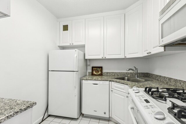 kitchen with light tile patterned flooring, a sink, white cabinetry, white appliances, and visible vents