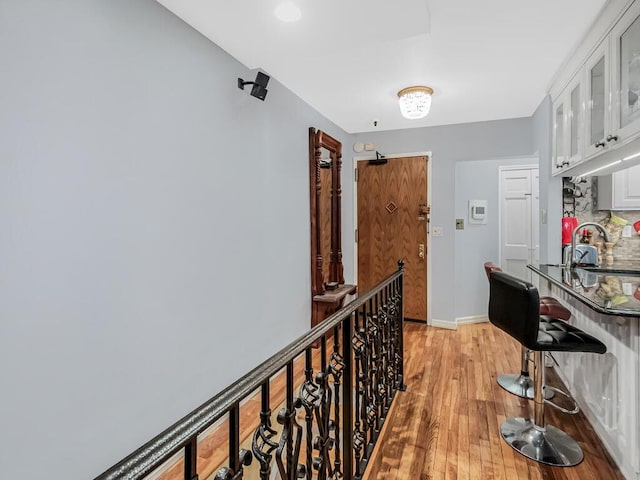 hallway with a sink, baseboards, and light wood-style flooring