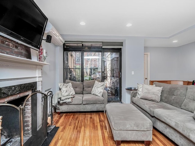 living room featuring recessed lighting, a fireplace, and wood finished floors