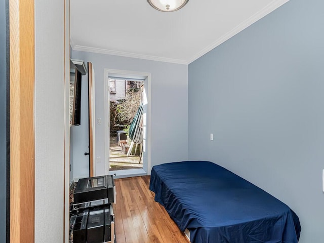 bedroom with hardwood / wood-style floors, crown molding, and access to outside