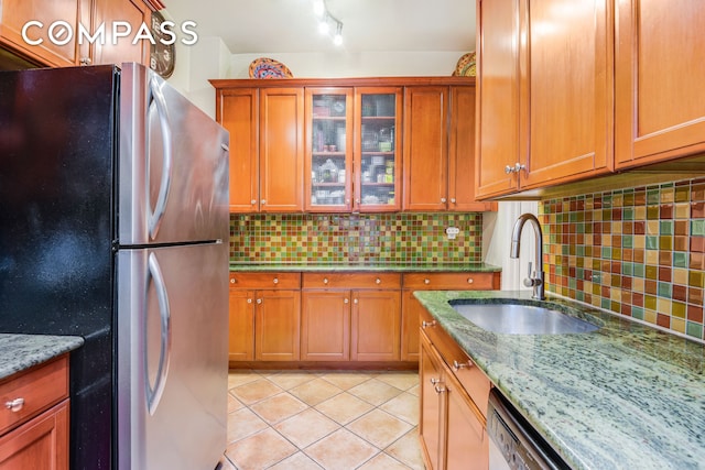 kitchen featuring light tile patterned flooring, tasteful backsplash, freestanding refrigerator, and a sink