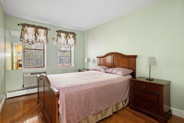 bedroom featuring hardwood / wood-style floors, baseboards, a wall mounted air conditioner, and a baseboard radiator