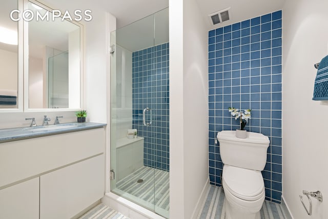 bathroom with a shower stall, vanity, baseboards, toilet, and visible vents