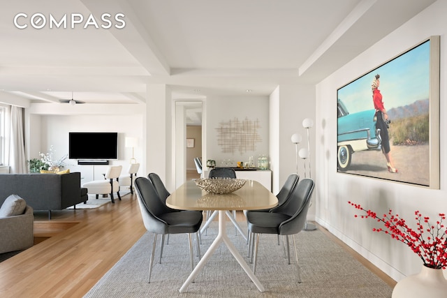 dining room featuring beam ceiling, wood finished floors, and baseboards