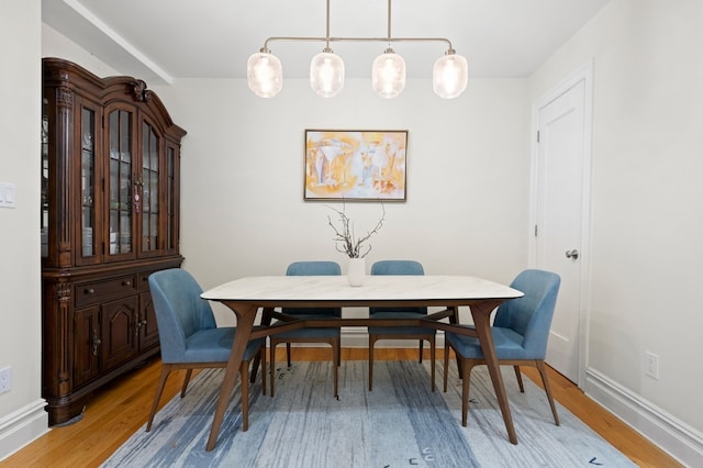 dining space featuring light wood-style flooring and baseboards