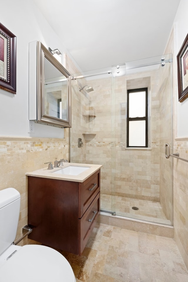 full bath with a shower stall, tile walls, toilet, wainscoting, and vanity