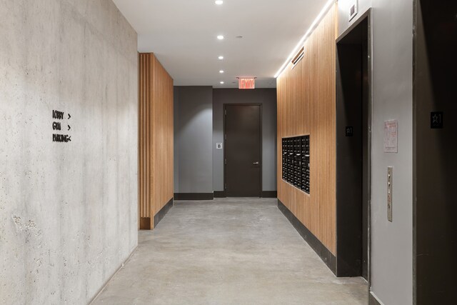 hallway featuring recessed lighting, mail area, and concrete flooring