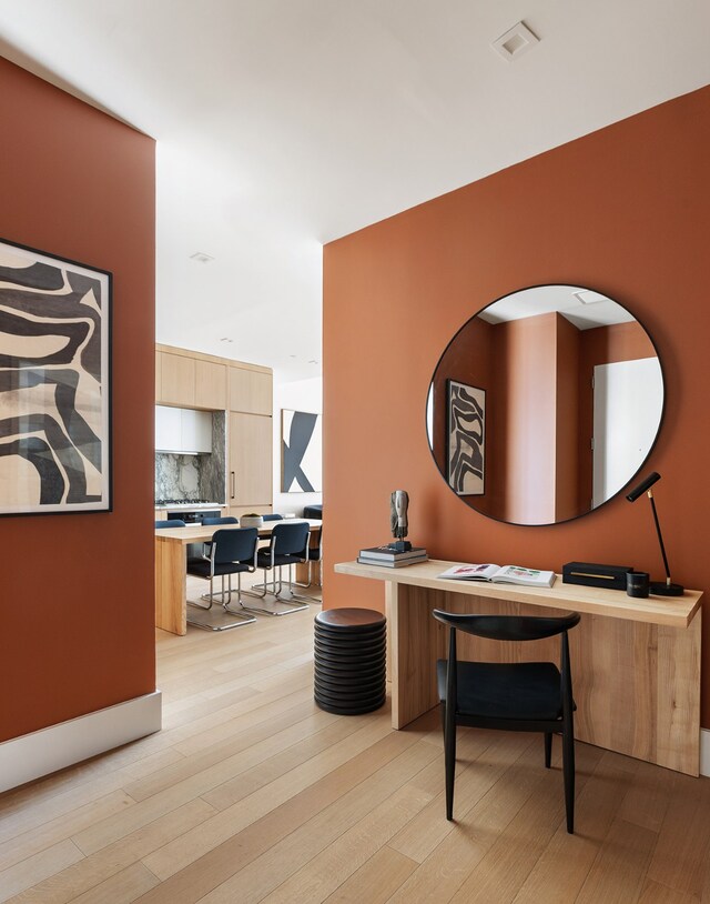 home office with light wood-style flooring and visible vents