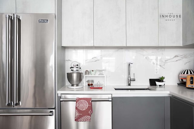 kitchen with high end fridge, a sink, light countertops, modern cabinets, and backsplash