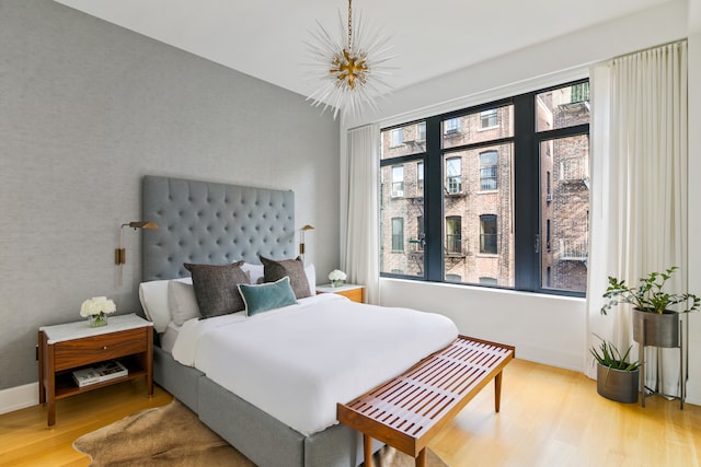 bedroom with baseboards, an inviting chandelier, and wood finished floors