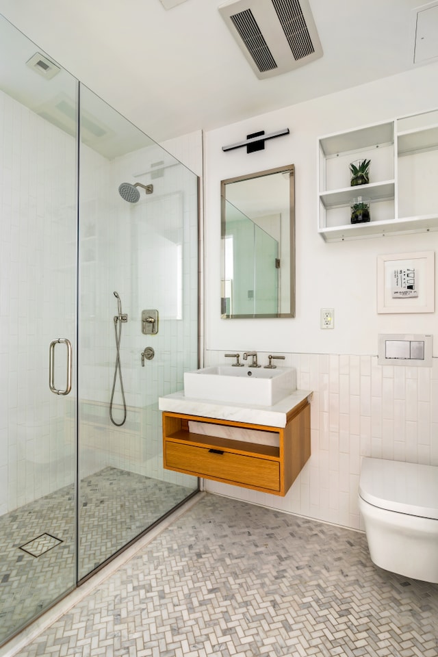 bathroom featuring toilet, a shower stall, vanity, tile walls, and a wainscoted wall