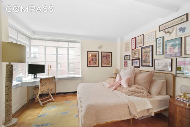 bedroom with built in desk, baseboards, and wood finished floors