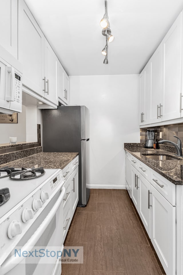 kitchen featuring white appliances, a sink, white cabinetry, baseboards, and dark wood-style floors