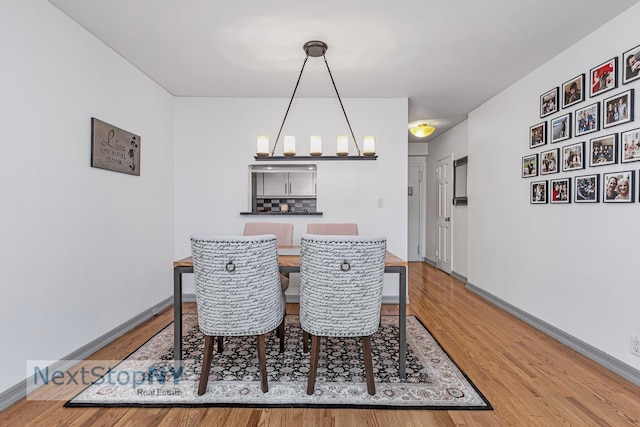dining room featuring light wood-style flooring, baseboards, and a chandelier