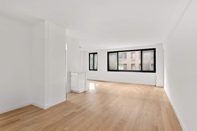 unfurnished room with light wood finished floors and baseboards