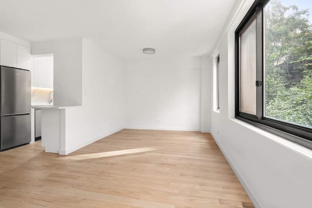 unfurnished room featuring baseboards and light wood-style floors