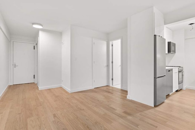 empty room featuring light wood-type flooring and baseboards