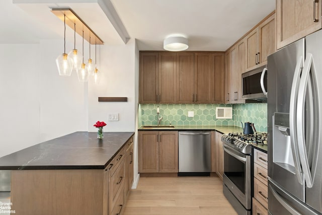 kitchen with dark countertops, backsplash, appliances with stainless steel finishes, and a peninsula