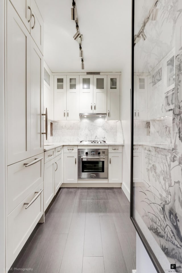 kitchen with backsplash, white cabinetry, gas stovetop, and oven