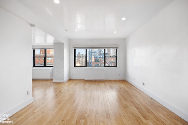 unfurnished room featuring recessed lighting, radiator, light wood-type flooring, and baseboards