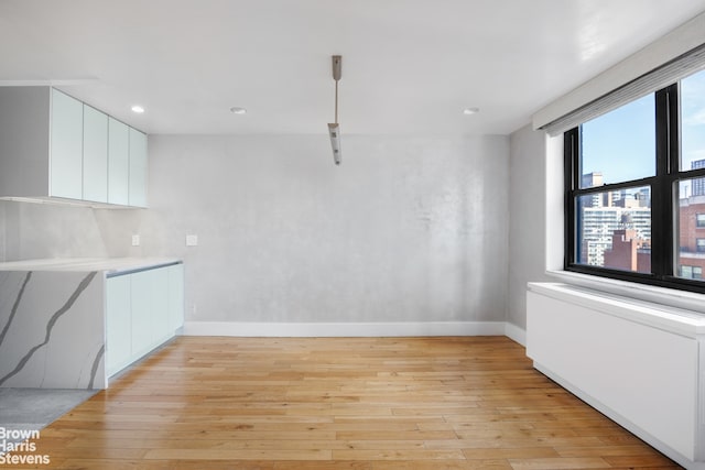 unfurnished dining area featuring recessed lighting, light wood-type flooring, and baseboards