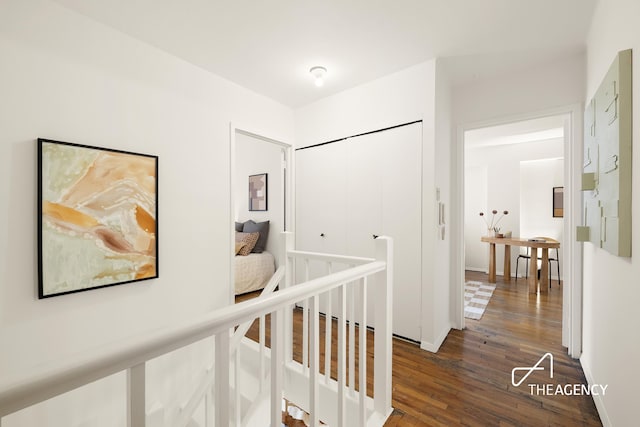 hall with an upstairs landing and dark wood finished floors