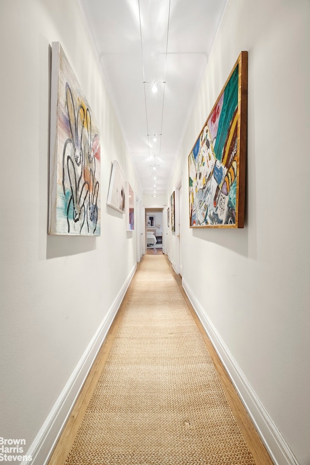 corridor with baseboards and wood finished floors