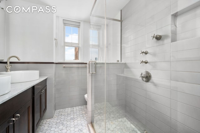 full bathroom featuring double vanity, a shower stall, tile walls, and a sink