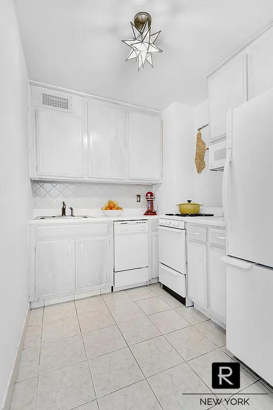 305 E 24th St Unit 5-S, New York City, NY 10010 - kitchen featuring white appliances, light countertops, and white cabinets