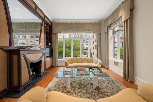 living room featuring a healthy amount of sunlight, crown molding, and wood finished floors