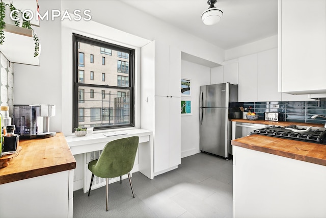 kitchen featuring freestanding refrigerator, white cabinets, stove, and wood counters