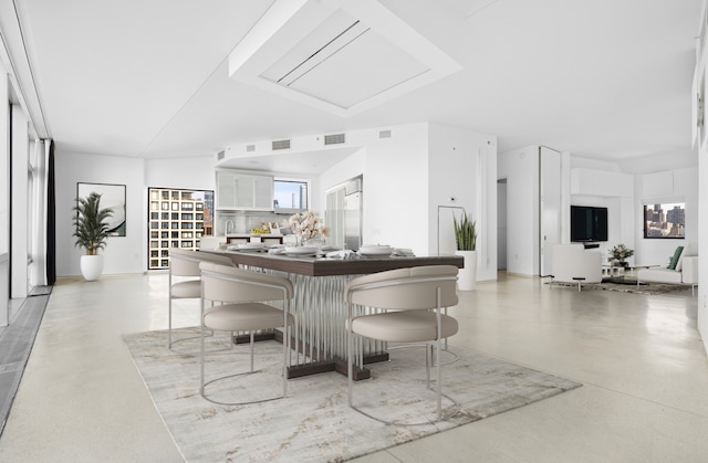 kitchen with visible vents, finished concrete floors, a breakfast bar, and white cabinets