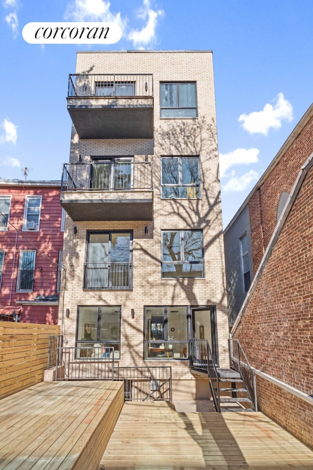 rear view of property featuring brick siding and a balcony