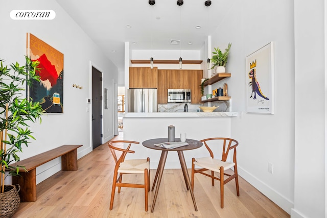 dining space with light wood-style floors, visible vents, and baseboards