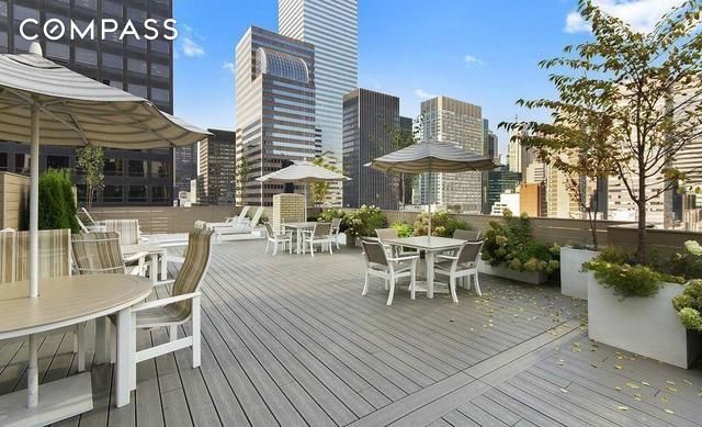 wooden terrace with outdoor dining space and a city view