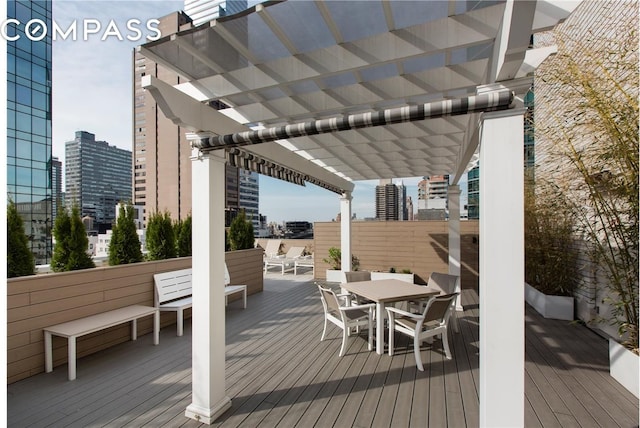 wooden terrace with outdoor dining area, a city view, and a pergola