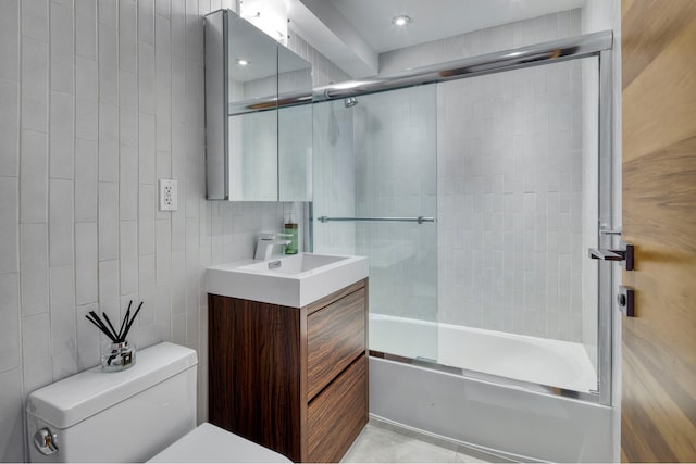 bathroom featuring vanity, tile walls, toilet, and combined bath / shower with glass door