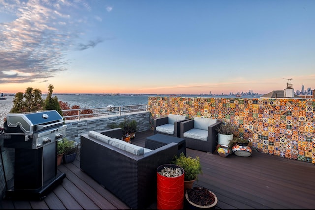 deck at dusk featuring a water view, area for grilling, and outdoor lounge area