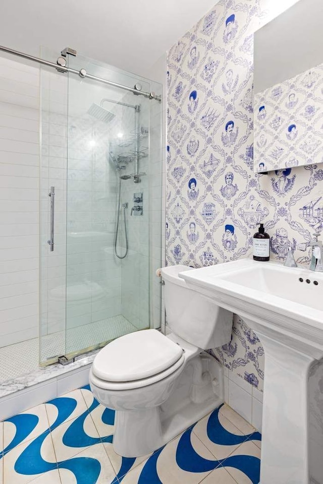 bathroom featuring tile patterned floors, wallpapered walls, toilet, and a stall shower