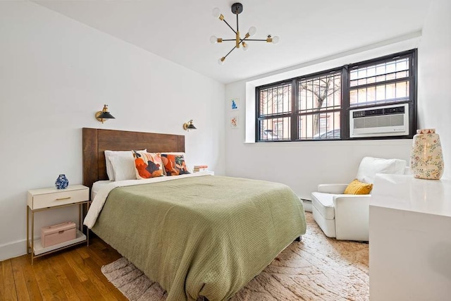 bedroom with a notable chandelier, a baseboard radiator, cooling unit, and wood finished floors