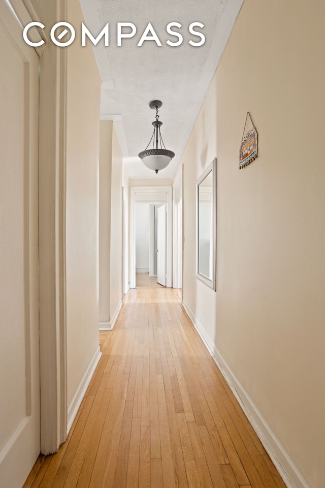 corridor with light wood-style flooring and baseboards