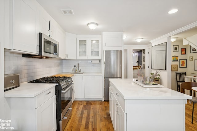 kitchen with light countertops, light wood finished floors, tasteful backsplash, and appliances with stainless steel finishes