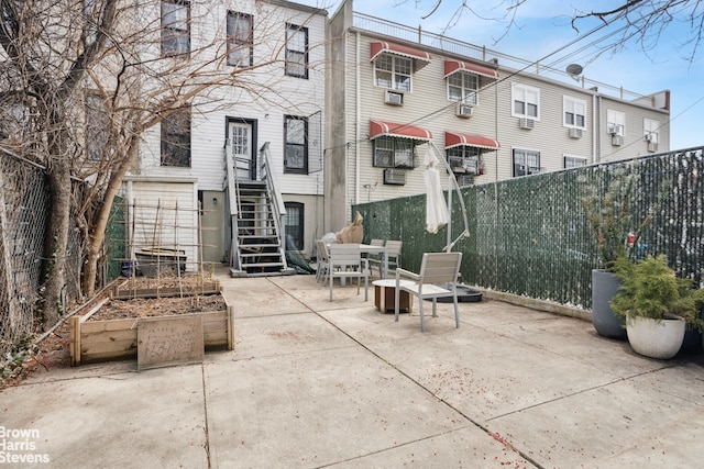 view of patio featuring a garden, stairway, outdoor dining space, and fence