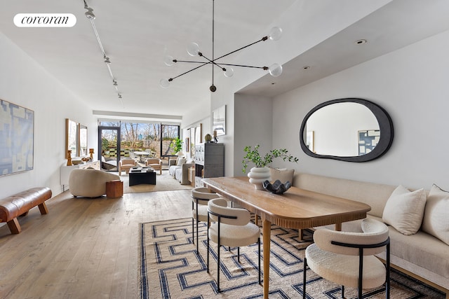 dining room featuring light wood-style flooring, rail lighting, visible vents, and a chandelier