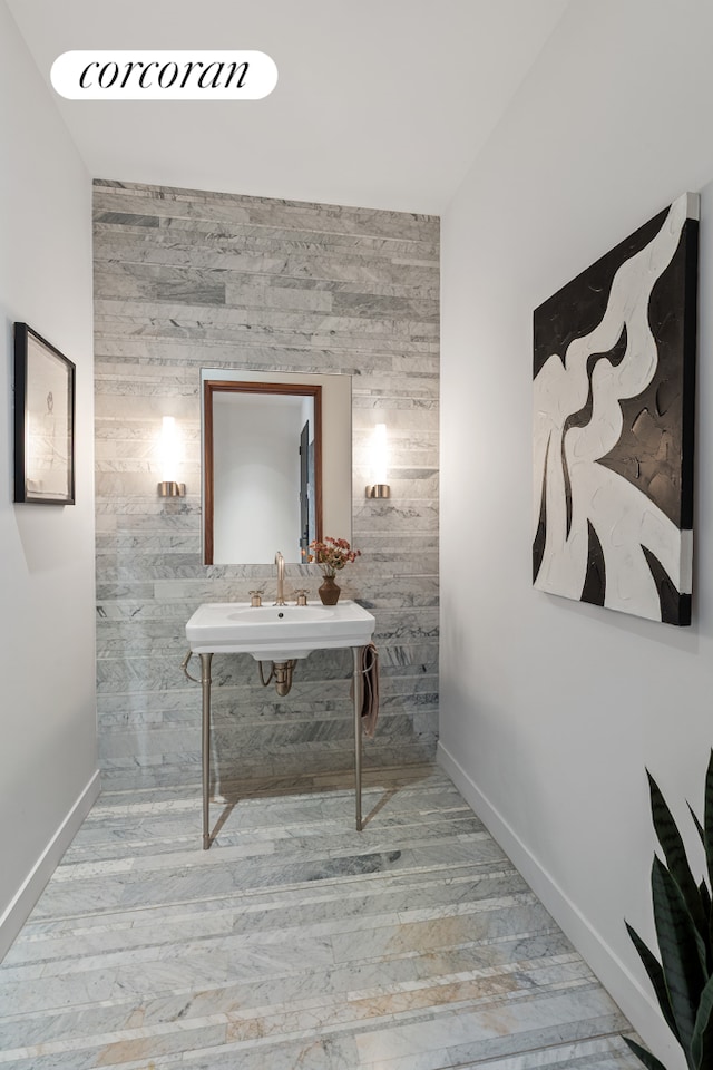 bathroom featuring a sink, baseboards, wood finished floors, and wood walls