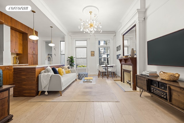 living room with light wood finished floors, visible vents, a high end fireplace, crown molding, and an inviting chandelier