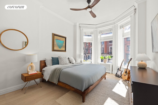 bedroom with baseboards, visible vents, light wood finished floors, ceiling fan, and crown molding