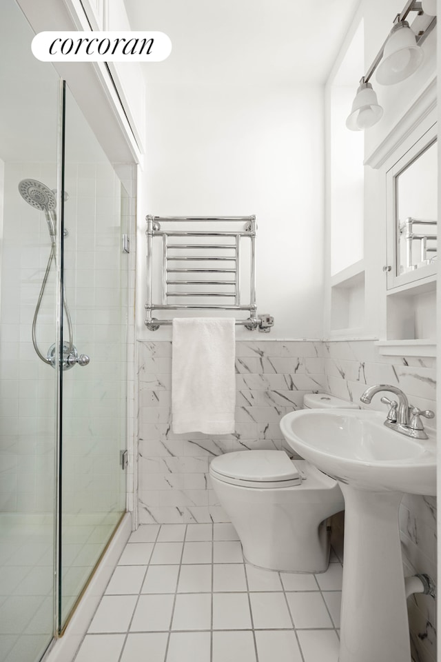 full bath featuring a wainscoted wall, a stall shower, tile patterned flooring, tile walls, and toilet